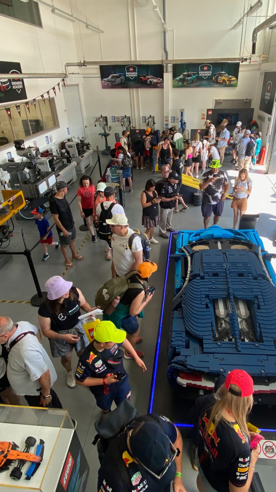 A crowd of people looking at models of LEGO cars